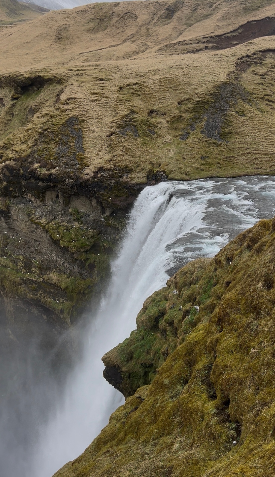 Skógafoss-style waterfall pouring over a moss-covered cliff